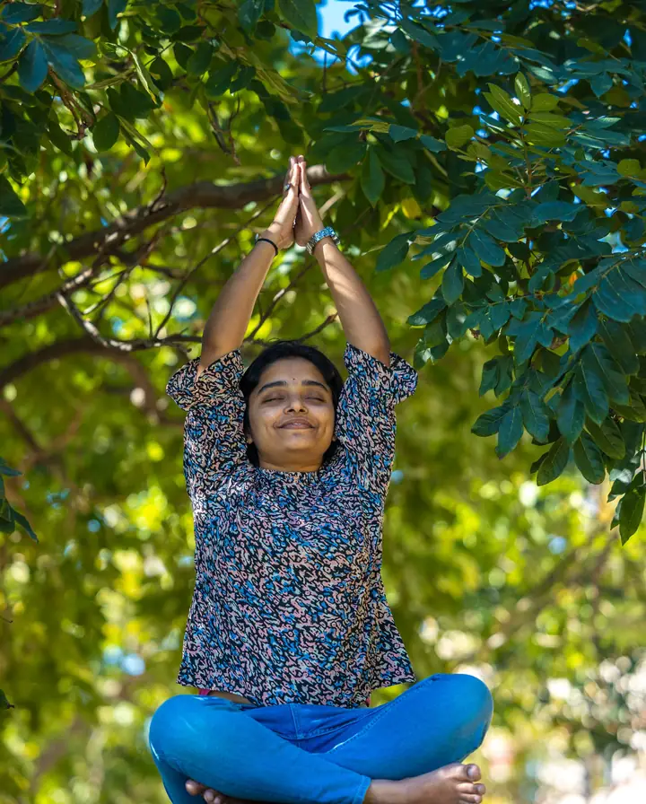 An Indian woman in a seated yoga stretch in a green park, steady daily habits instead of crash diets